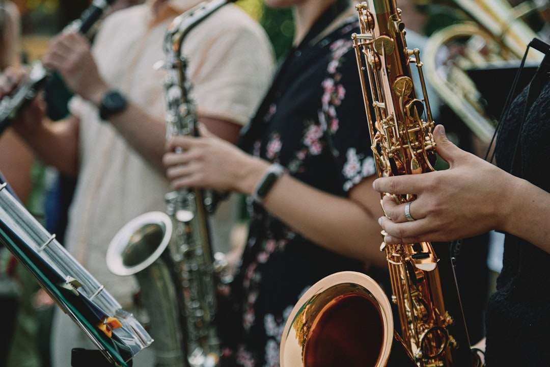 person in black and white floral shirt playing saxophone