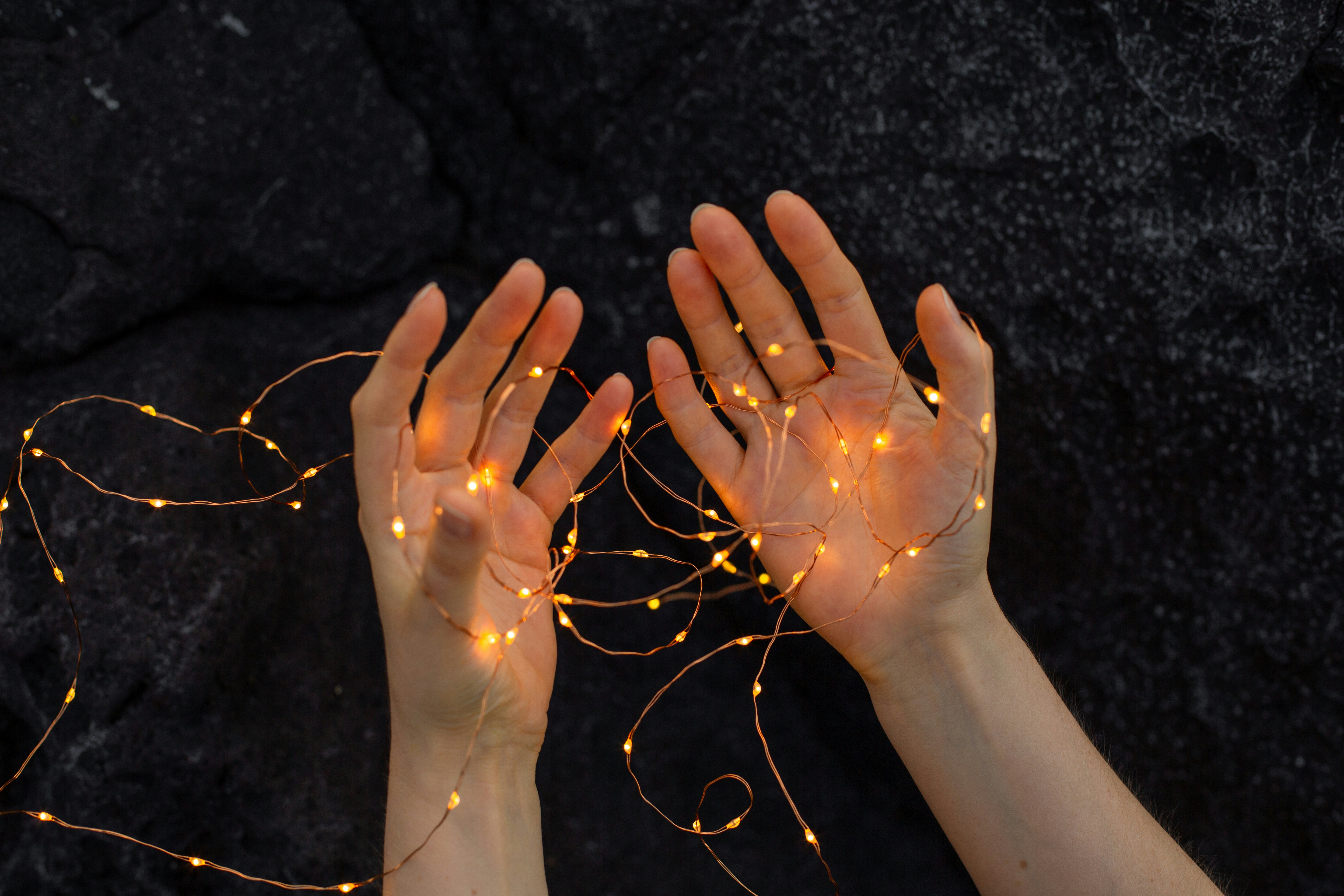 Illuminated hands with LED lights and gray rocks in the background