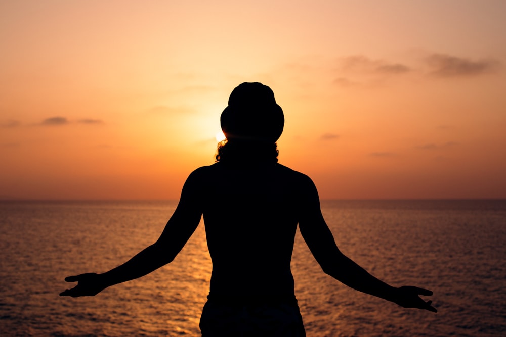 silhouette of man standing on beach during sunset