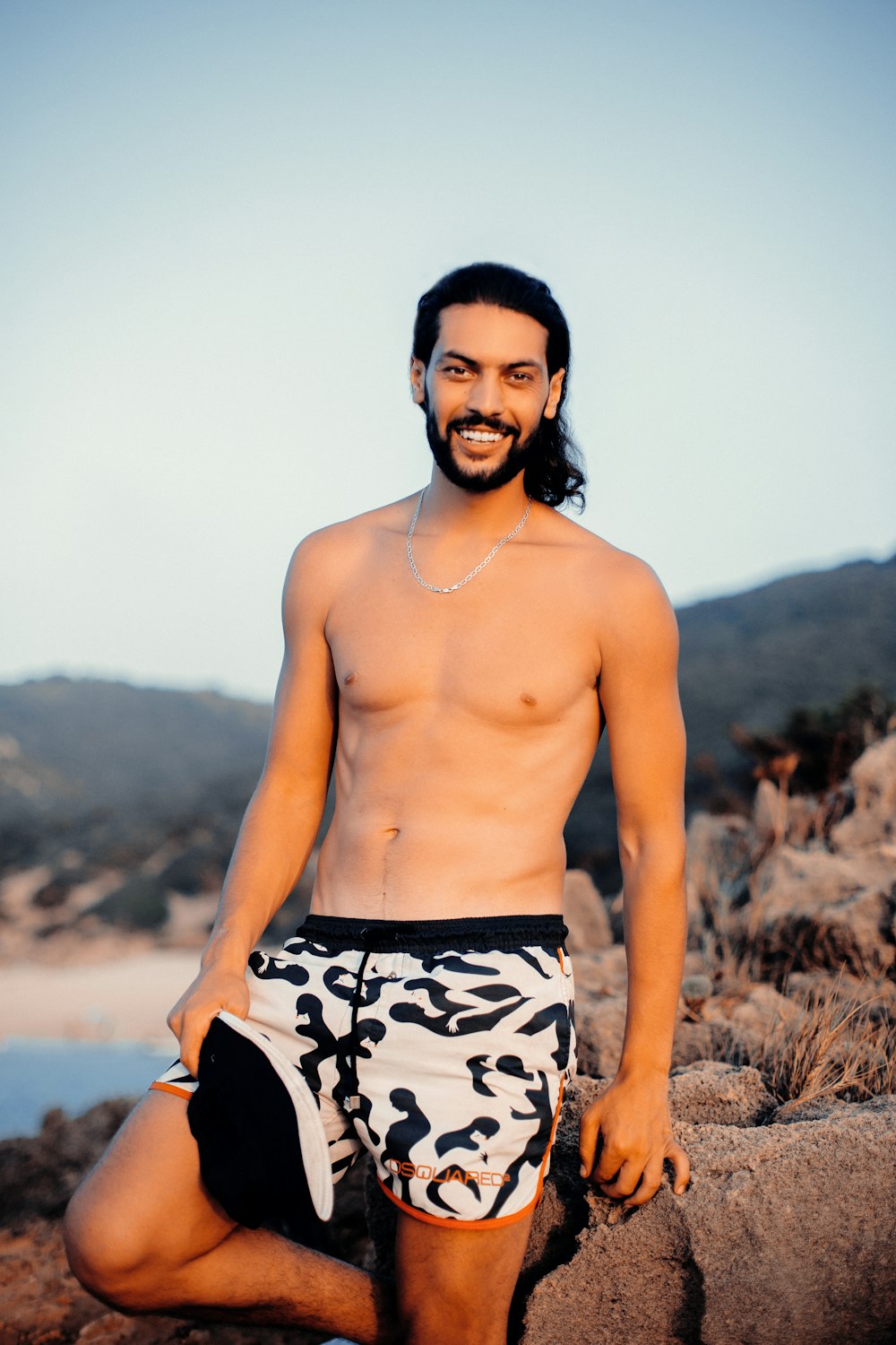 topless man in black and white shorts standing on brown field during daytime