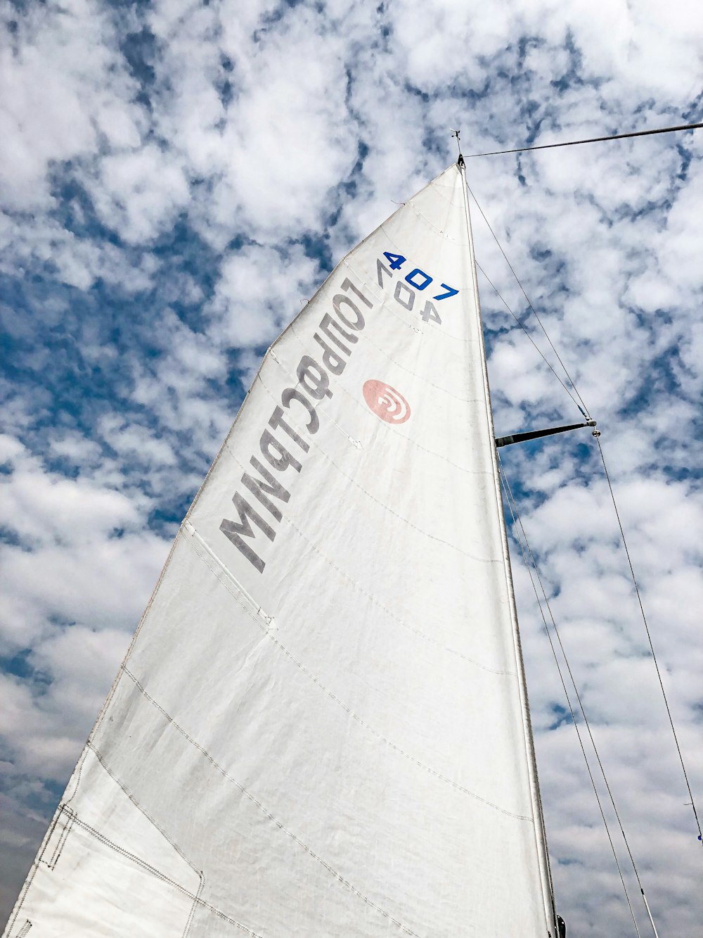 white sail boat on sea under blue sky and white clouds during daytime