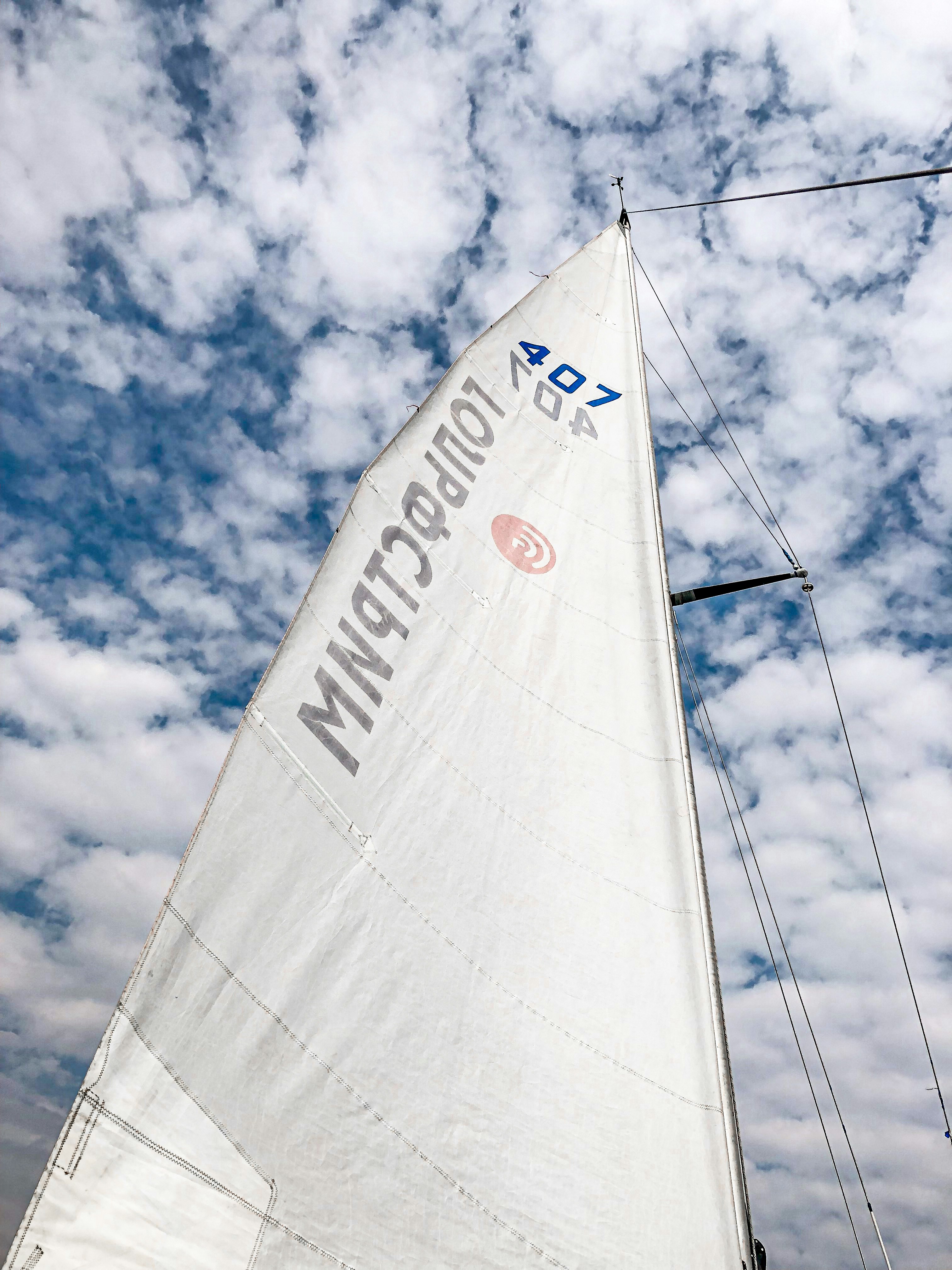 white sail boat on sea under blue sky and white clouds during daytime