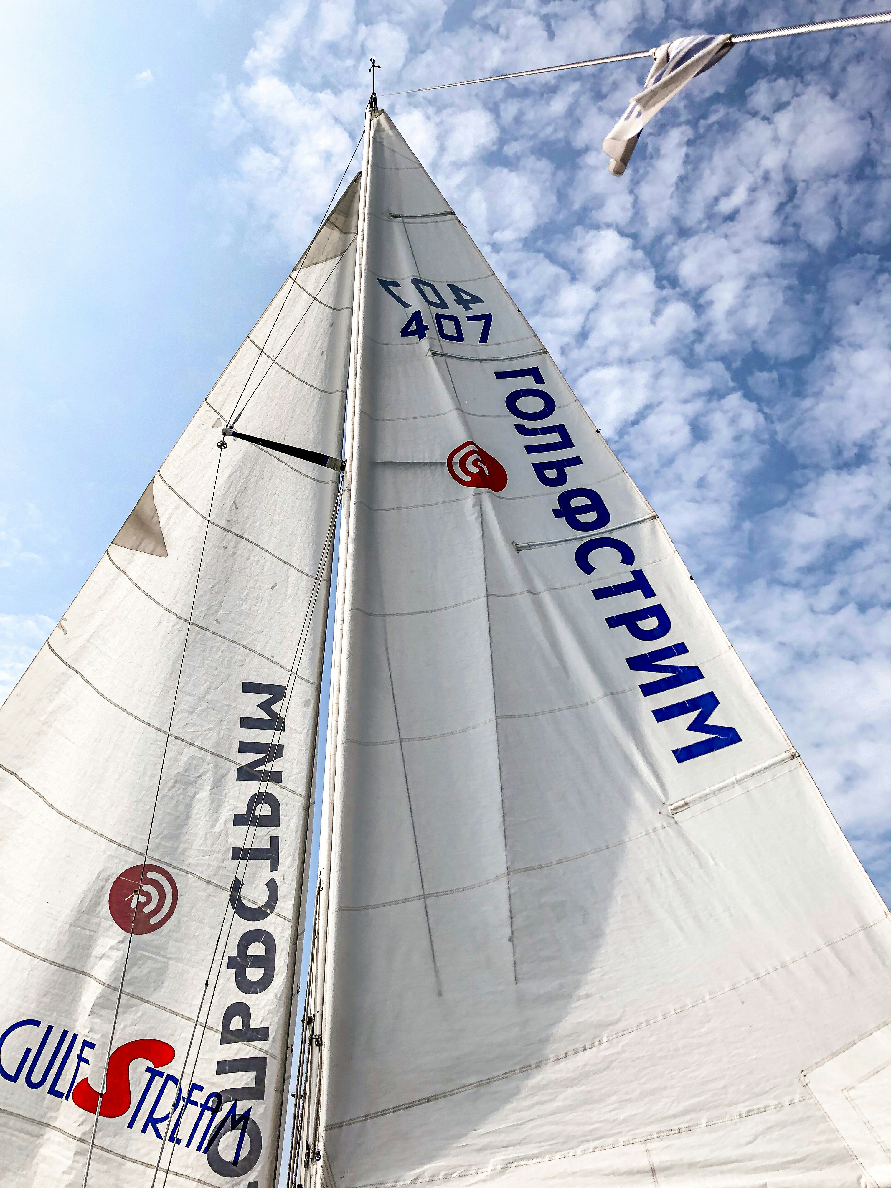 white sail boat on mid air under blue sky and white clouds during daytime