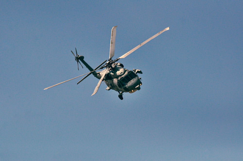 black and green helicopter flying in the sky