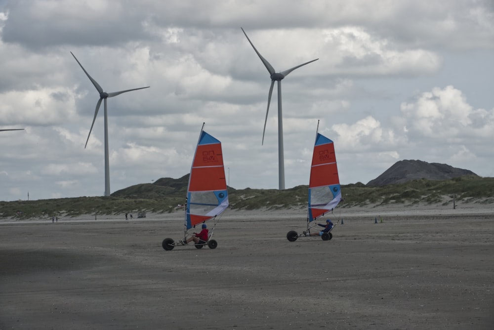 white and red wind turbines on gray asphalt road under gray cloudy sky during daytime