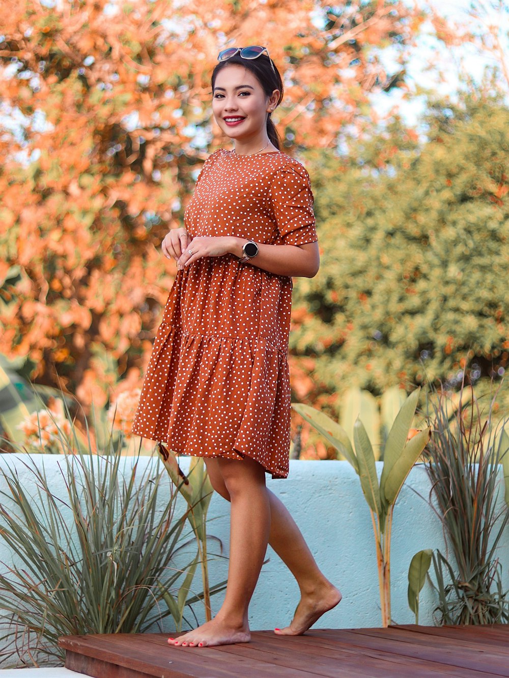 woman in red and white polka dot dress standing near green plants during daytime