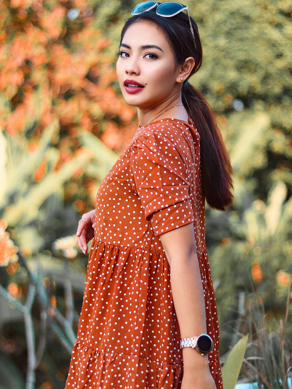 woman in red and white polka dot dress standing on grass field during daytime