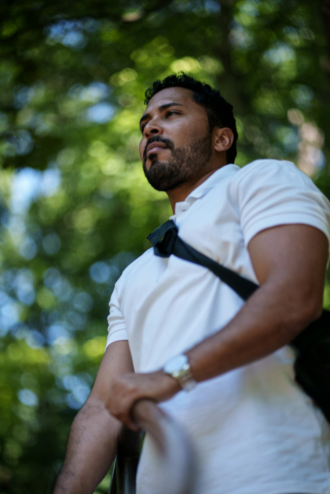 man in white polo shirt standing near green trees during daytime