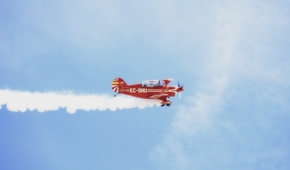 red and white jet plane in mid air during daytime