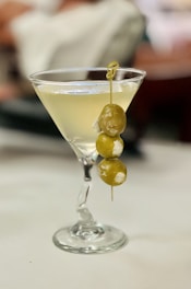 A gel wax martini candle in a clear martini glass with a wax olive garnish.