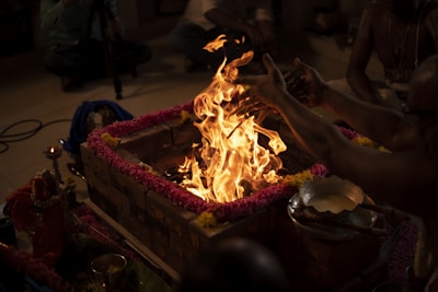 A vibrant hawan kund with flames rising, surrounded by samagri items like guggul and samidha sticks.
