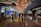 A modern airport terminal with high ceilings and long corridors. Information displays and signboards direct travelers towards gates C1-C29. People are moving with luggage, some checking flight information on the screens.