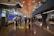 A modern airport terminal with high ceilings and long corridors. Information displays and signboards direct travelers towards gates C1-C29. People are moving with luggage, some checking flight information on the screens.