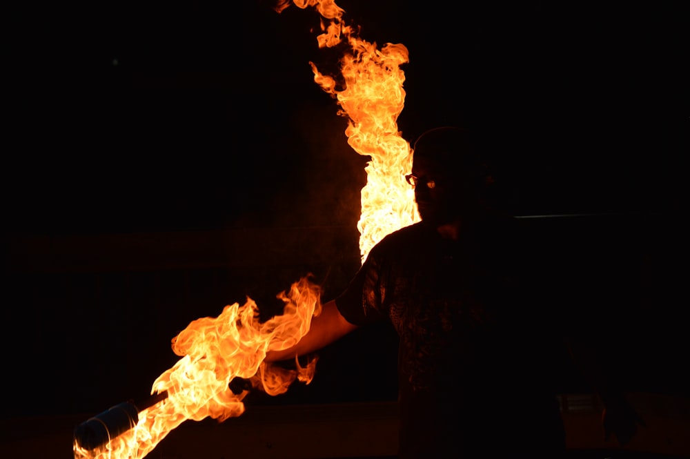 man in black shirt standing in front of fire