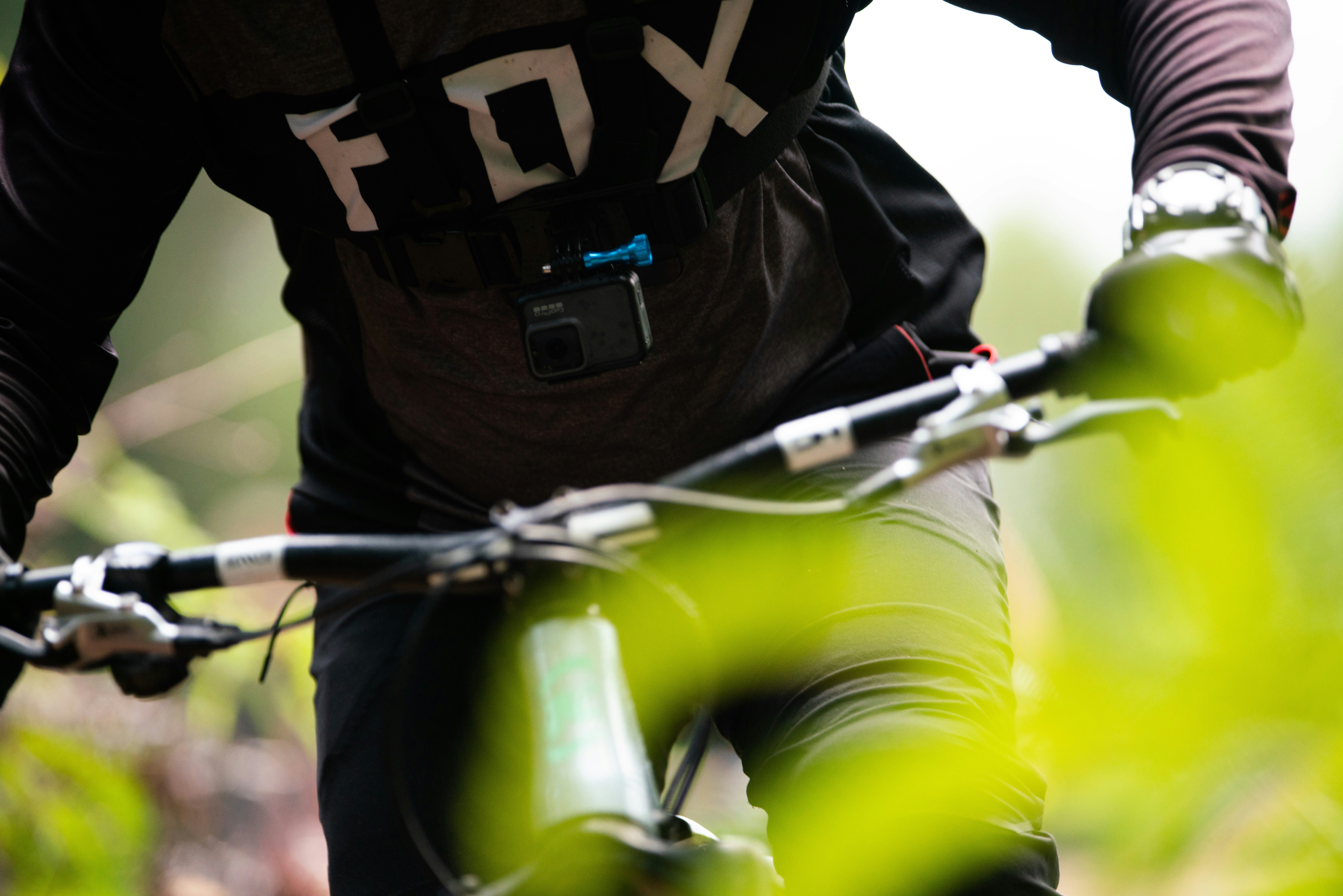 person in black and white long sleeve shirt and green pants riding on bicycle during daytime