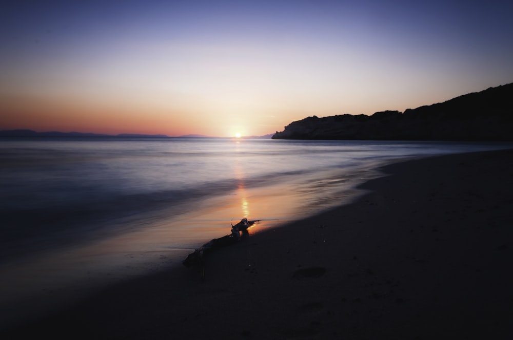 person walking on beach during sunset