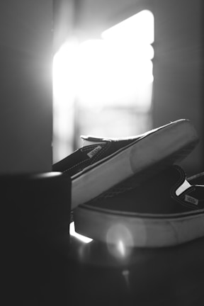 Pair of black rubber shoes with subtle star patterns shining under soft light.