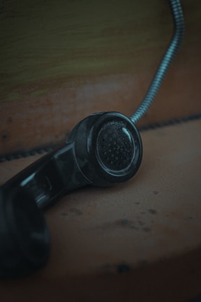 black corded telephone on brown wooden table