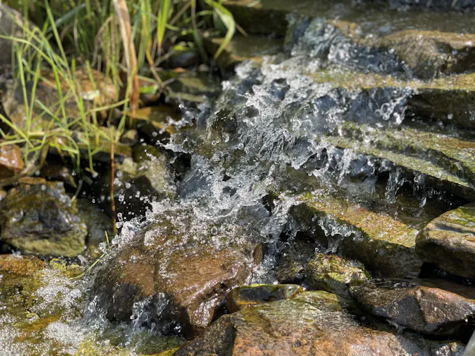 Water flowing over gray rocks, the kind of natural limestone spring setting that gives Roaring Spring, PA its name
