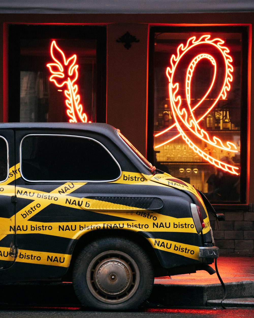 yellow and black car parked beside red building