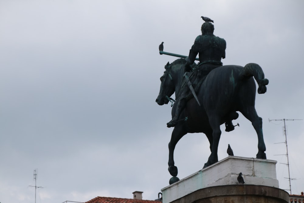 man riding horse statue under white sky during daytime