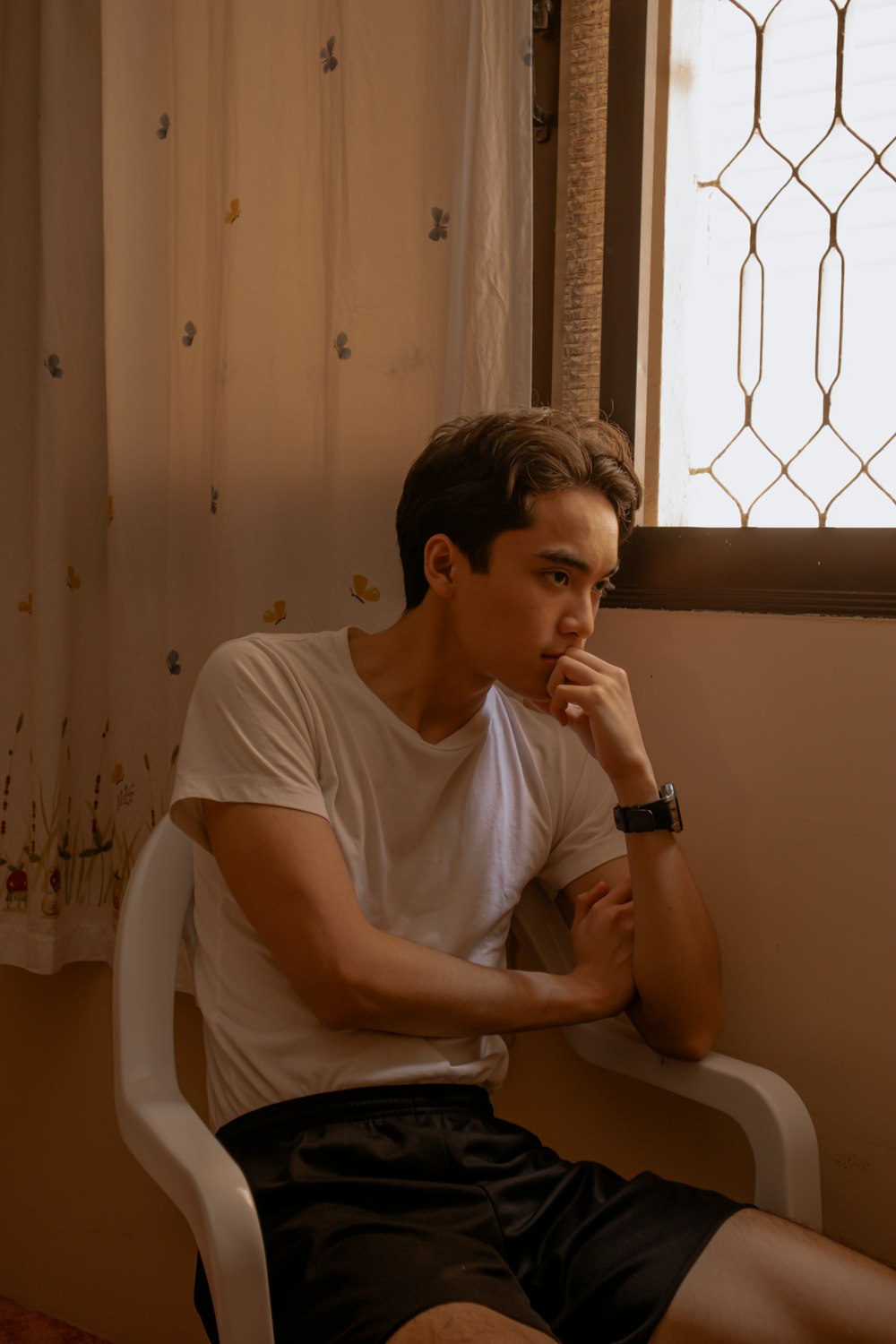 man in white tank top sitting on white plastic chair