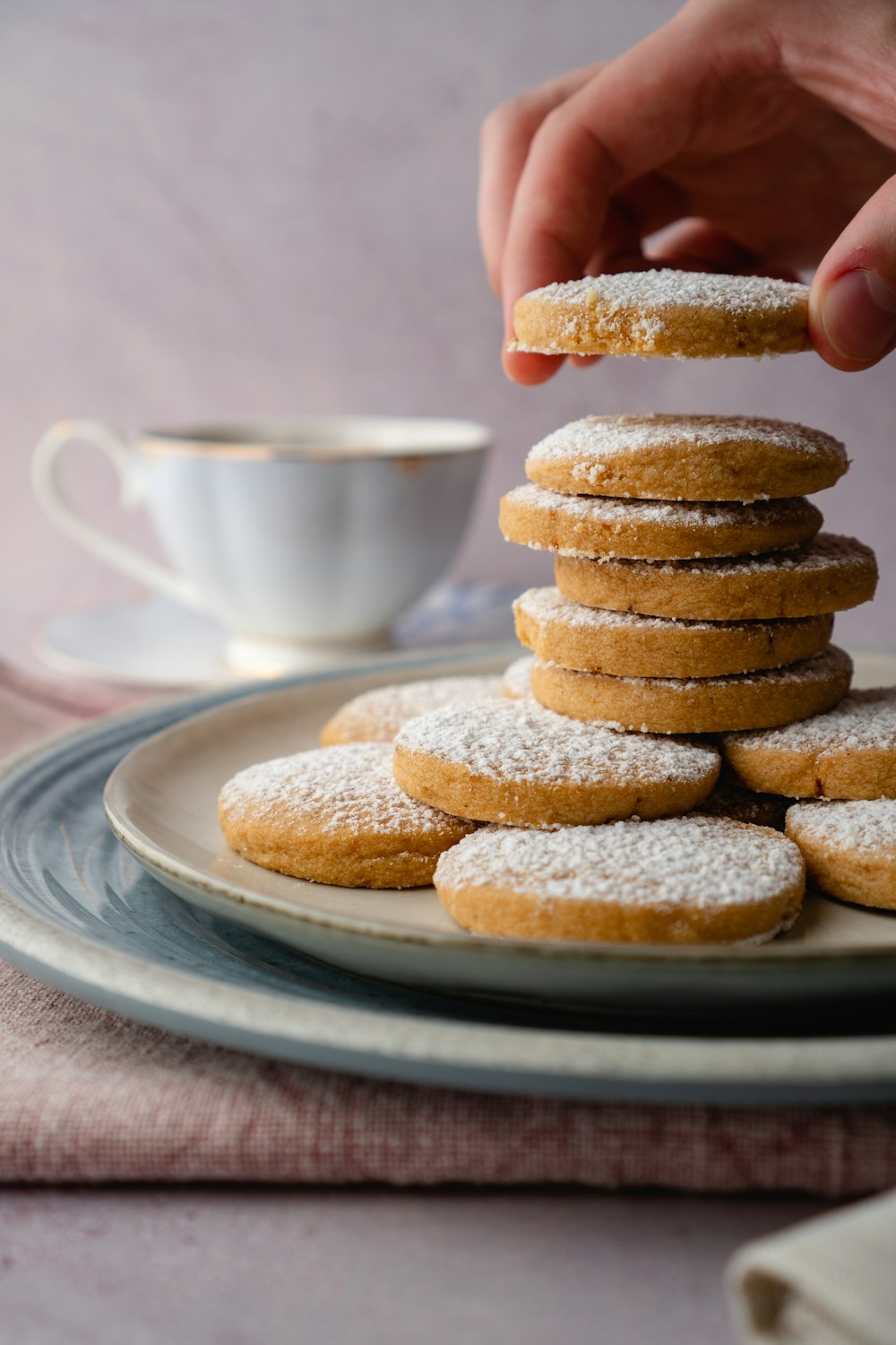 person holding white ceramic mug with brown cookies