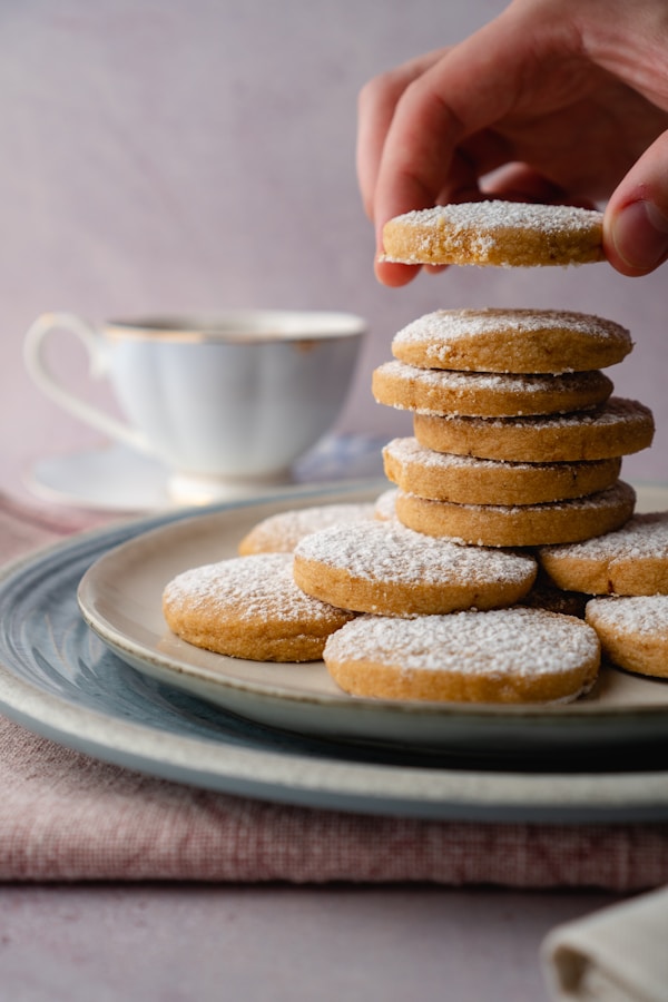 Person holding white ceramic mug with brown cookies