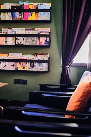 A cozy reading nook with built-in shelves and a charcoal accent wall finished in textured wallpaper.