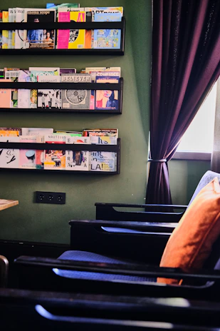 A cozy reading nook with soft beige tones and a stack of finance magazines on a wooden table.