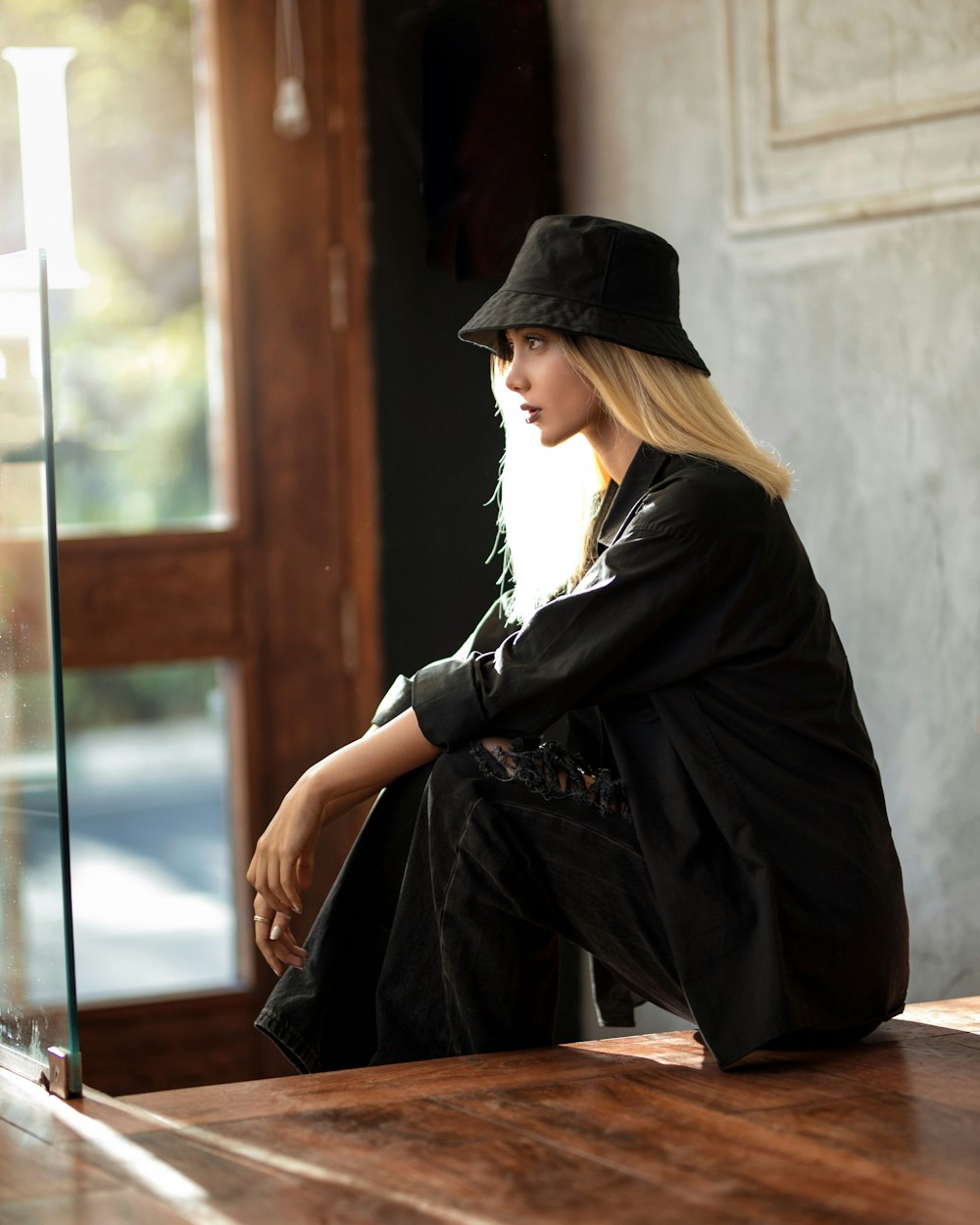 woman in black long sleeve dress and black hat sitting on brown wooden bench