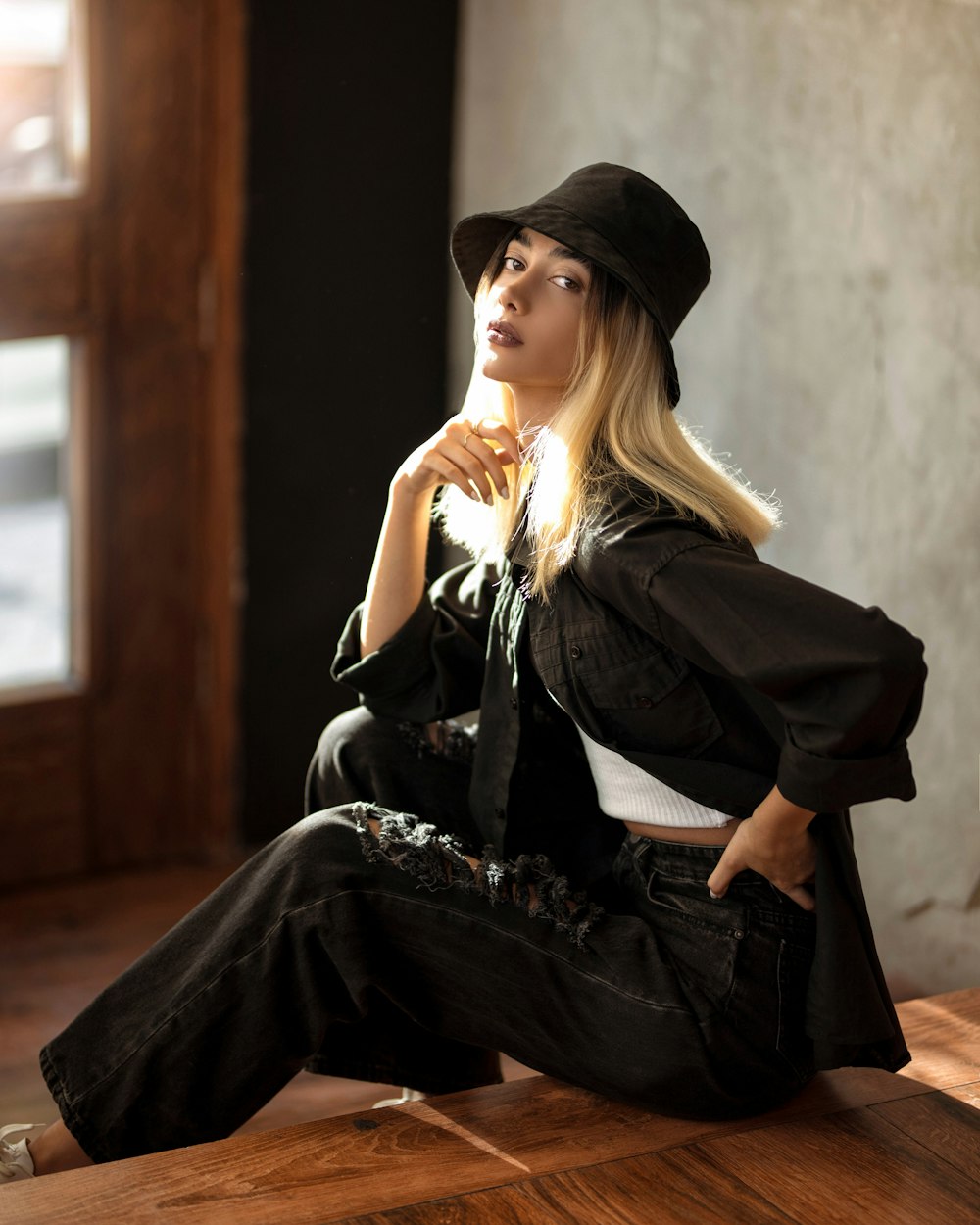 woman in black long sleeve dress and black hat sitting on brown wooden stairs