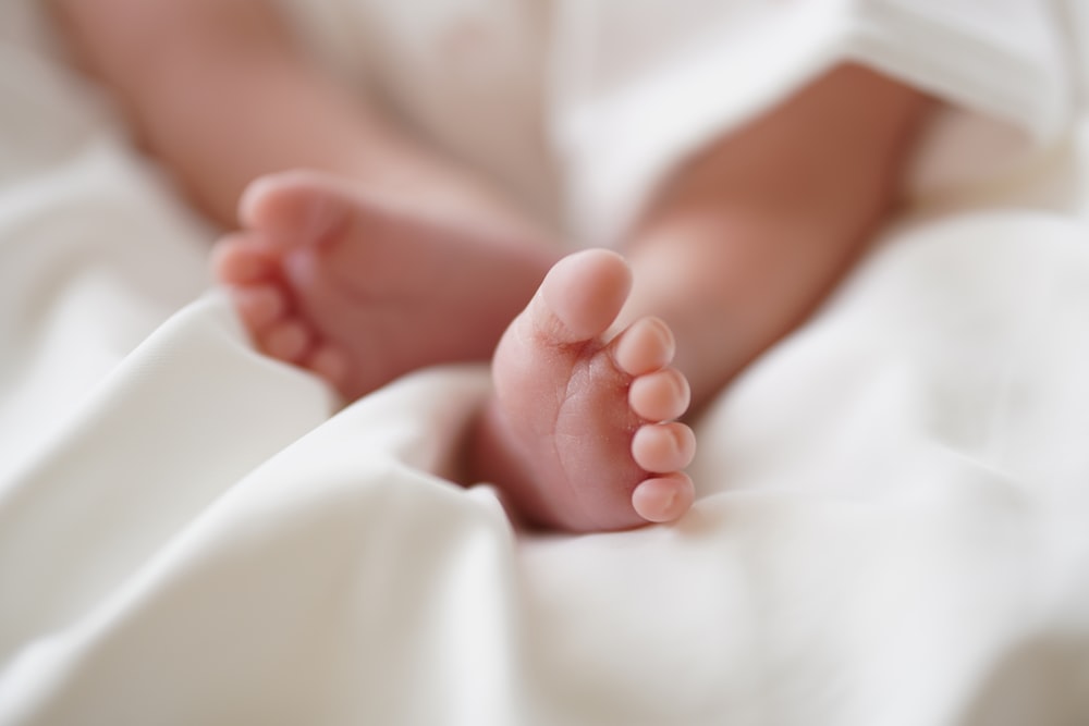 babys feet on white textile