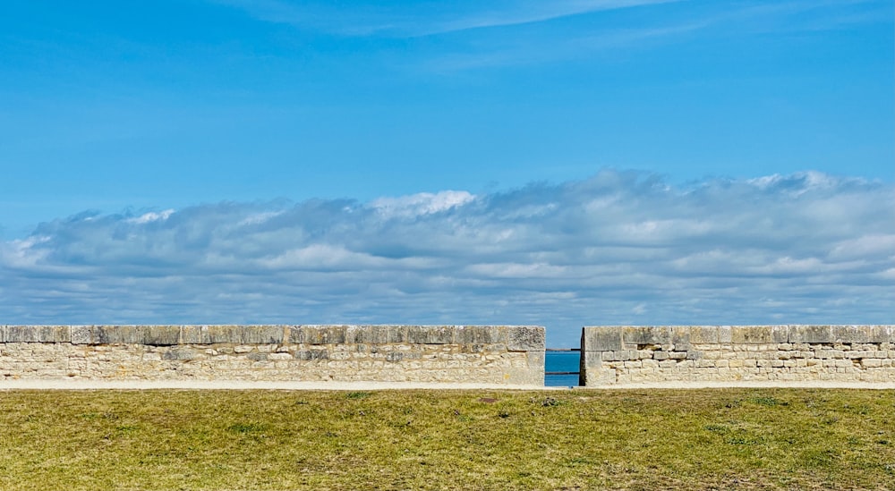 parede de concreto branco no campo de grama verde sob o céu azul durante o dia