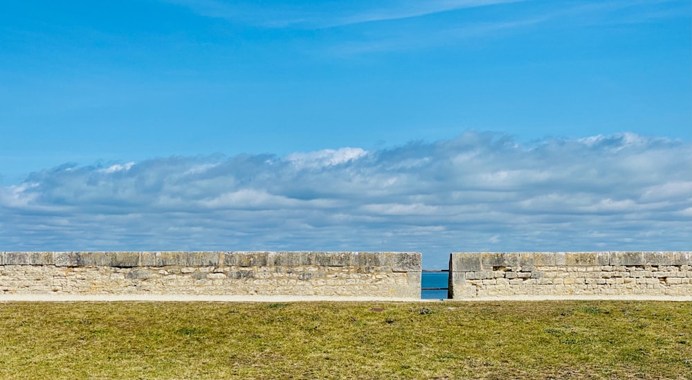 Pared de hormigón blanco en campo de hierba verde bajo cielo azul durante el día