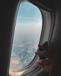 A cheerful traveler using a smartphone to book flights with a city skyline in the background.
