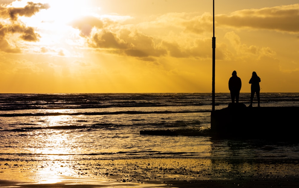silhouette of man fishing on sea during sunset