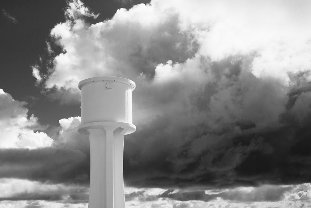 grayscale photo of round concrete tower under cloudy sky