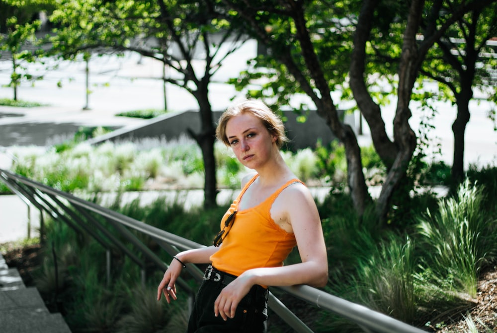 woman in orange tank top and black pants holding black bag