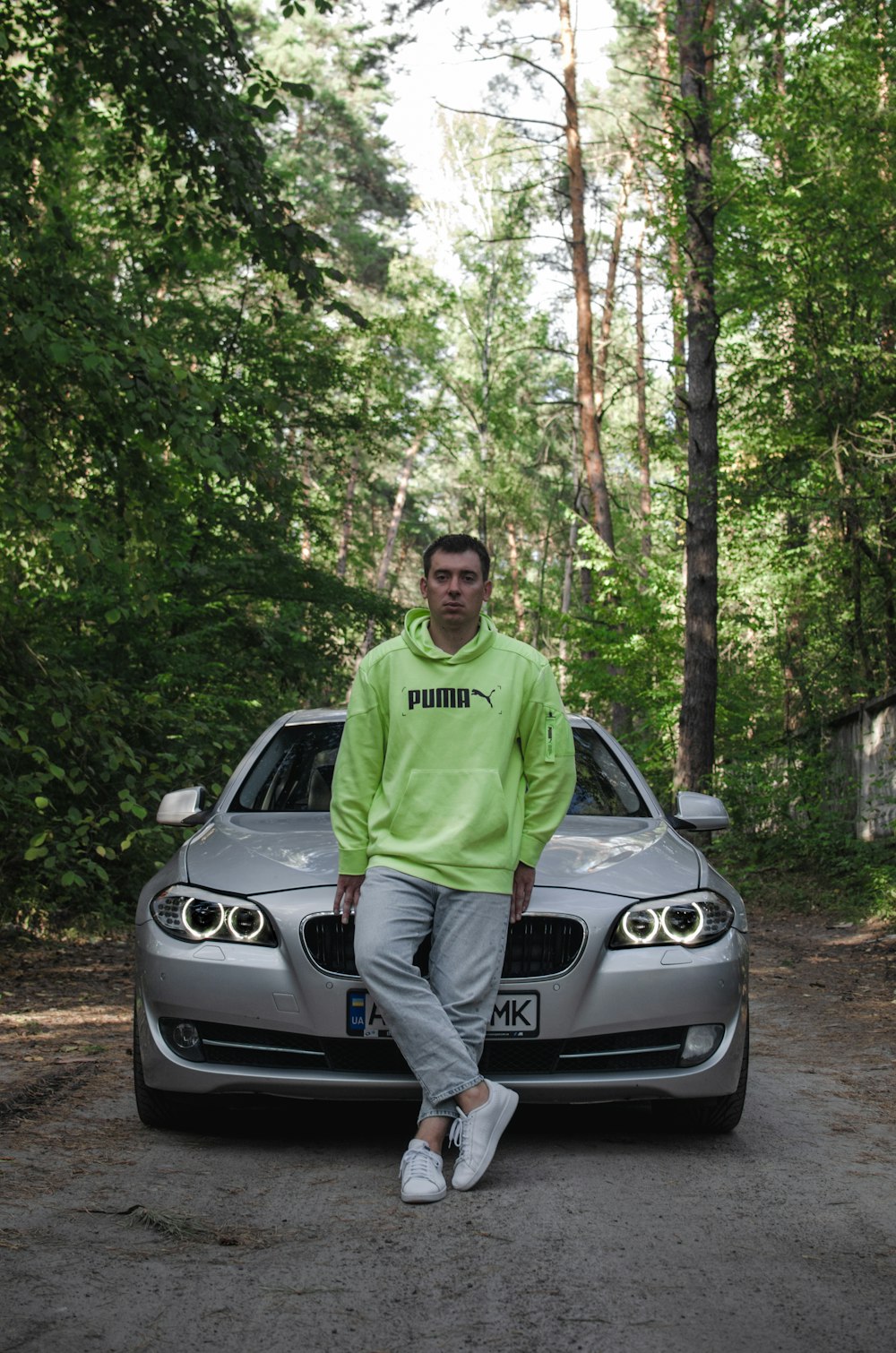 homme en t-shirt à col rond vert debout à côté de la voiture argentée