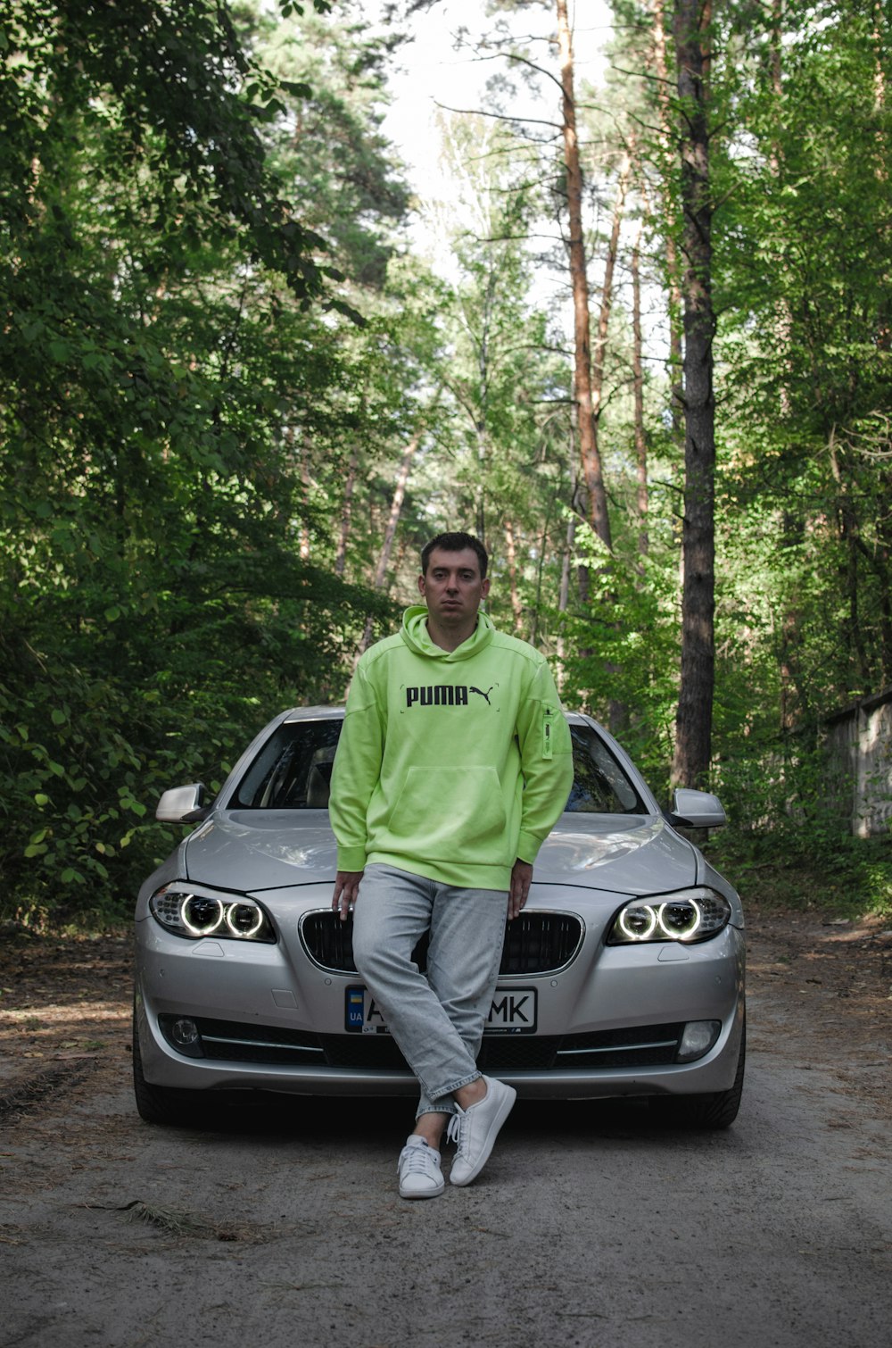 man in green crew neck t-shirt standing beside silver car