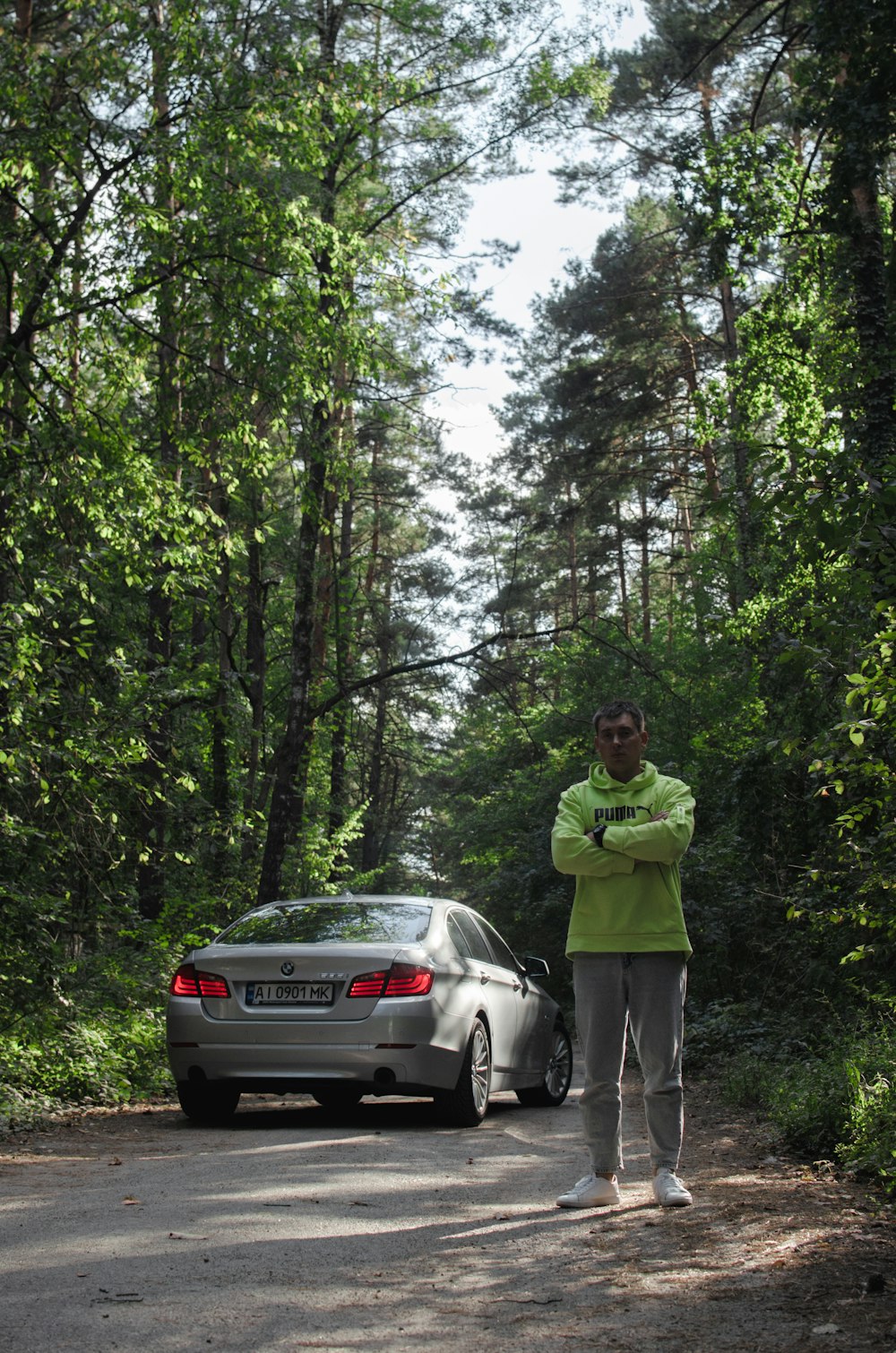 man in green jacket standing beside silver car