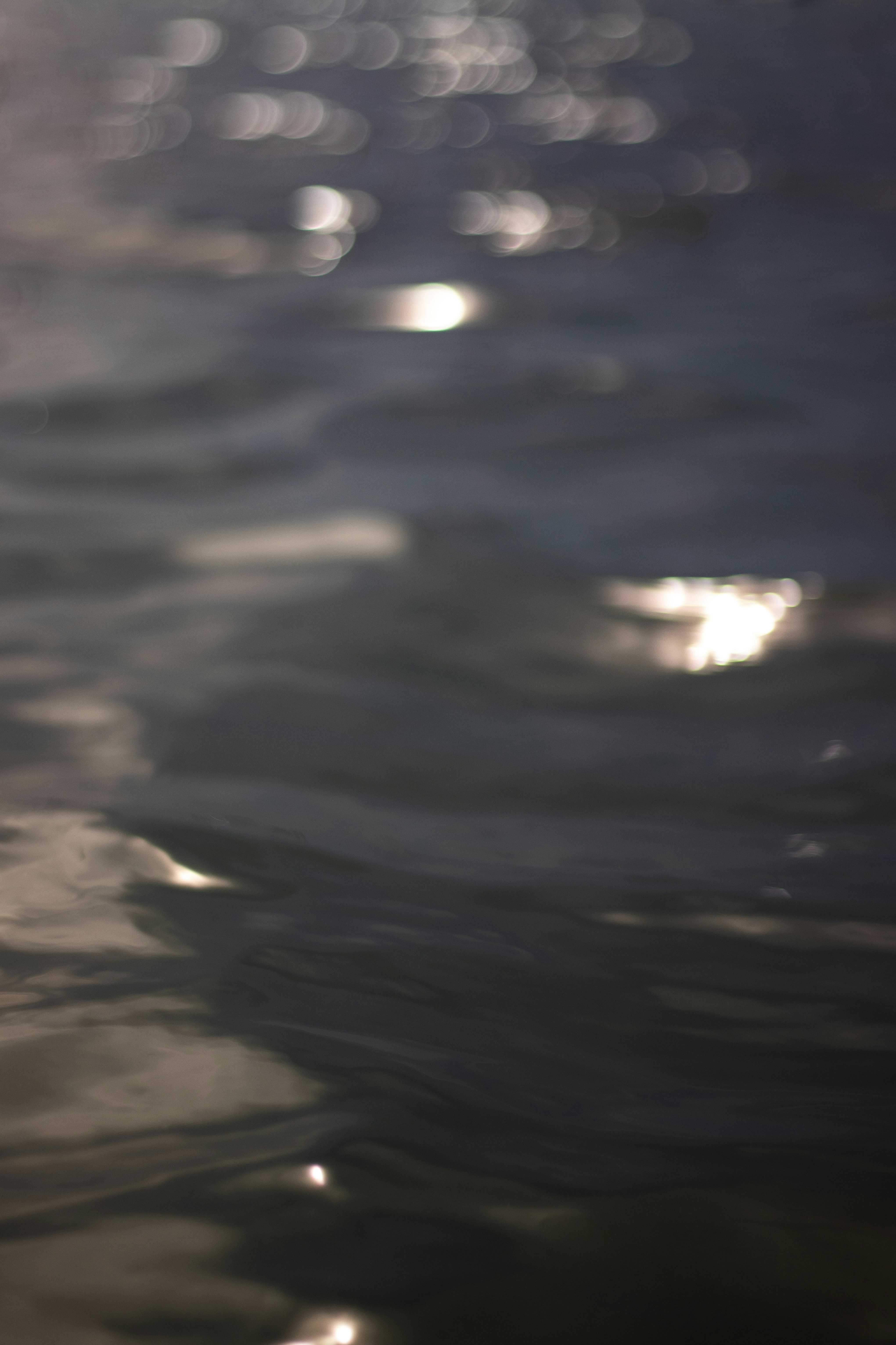 Water surface at dusk — deep shadows, luminous reflections, dark moody atmosphere, cinematic light