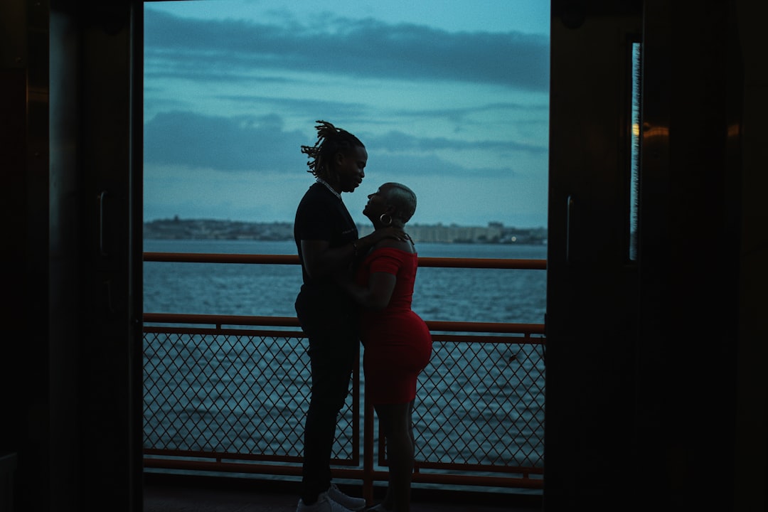 man and woman kissing near body of water during daytime