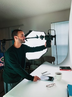 man in green sweater holding black and red power tool