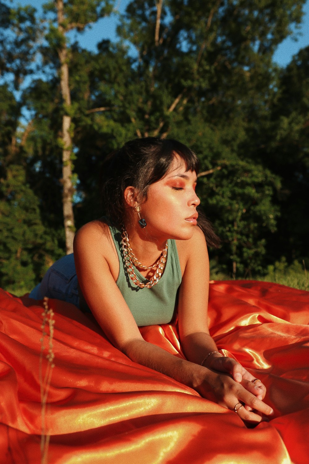 Femme en robe orange sans manches assise sur textile rouge