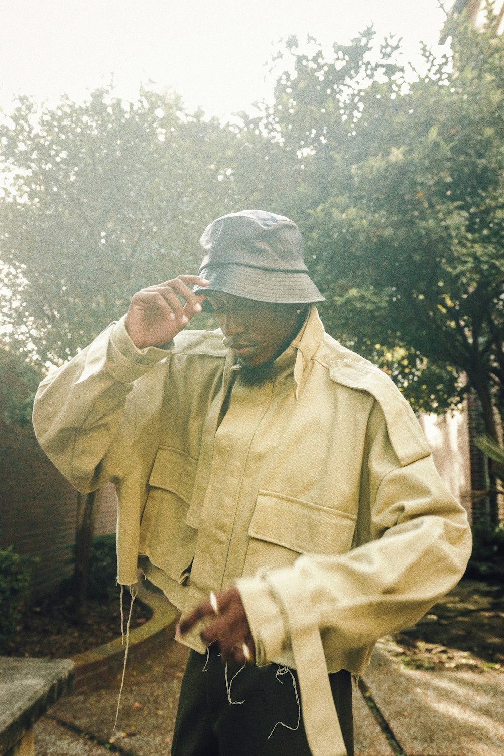 man in brown jacket and gray knit cap standing near green trees during daytime