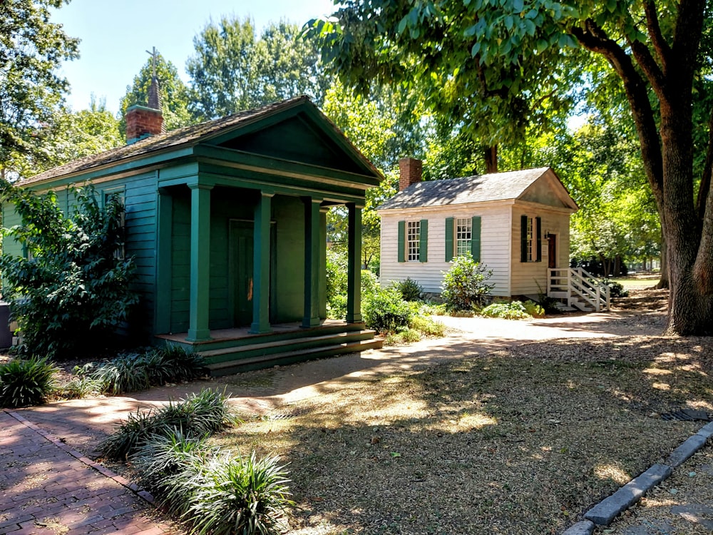 green and white wooden house near green trees during daytime