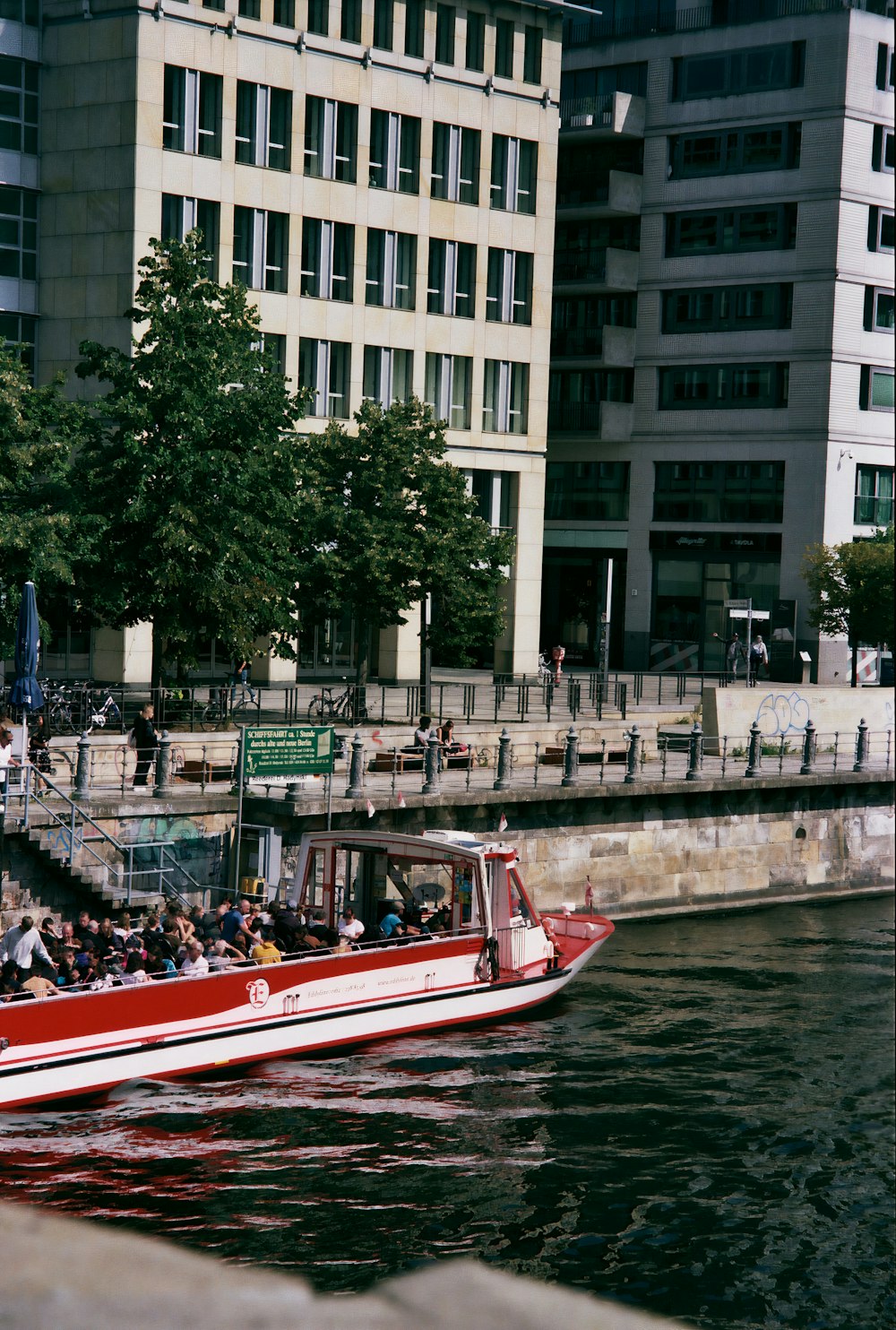 personas que viajan en bote rojo y blanco en el río durante el día