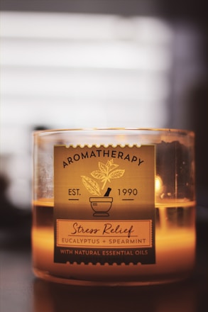 A candle labeled 'Aromatherapy Stress Relief' with eucalyptus and spearmint essential oils. The design includes a mortar and pestle illustration, creating a soothing and relaxing atmosphere.